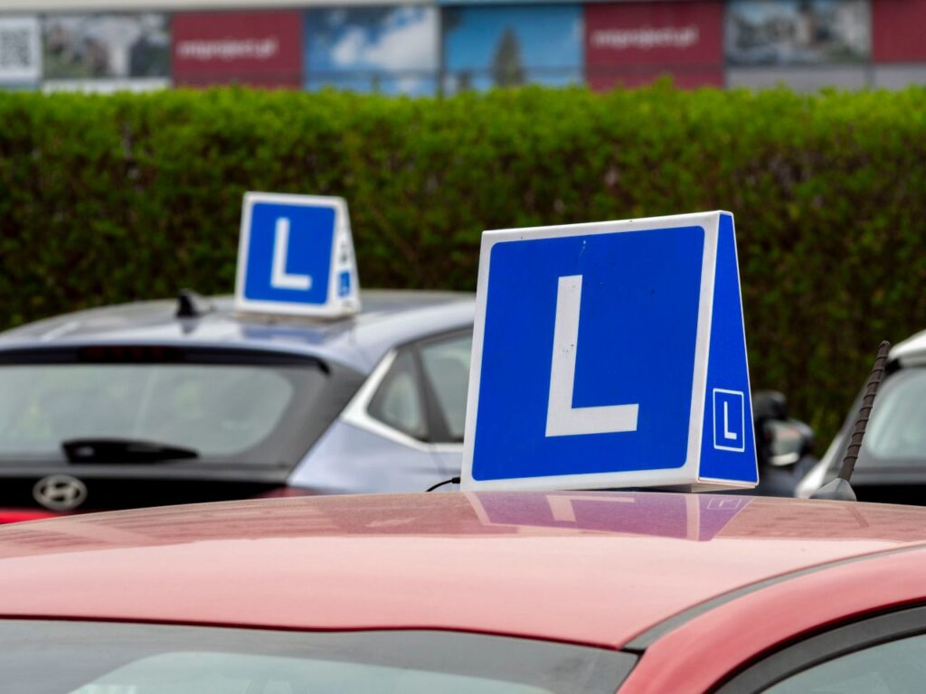 Cars with learning signs parked outdoors in Wrocław, Poland, at a driving school training area.